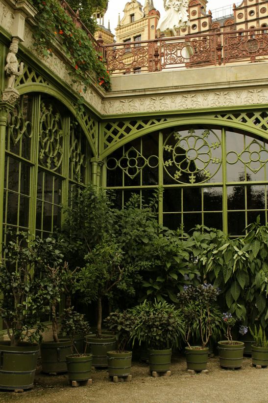 A woman is sitting at a desk with a laptop and a vase of flowers.