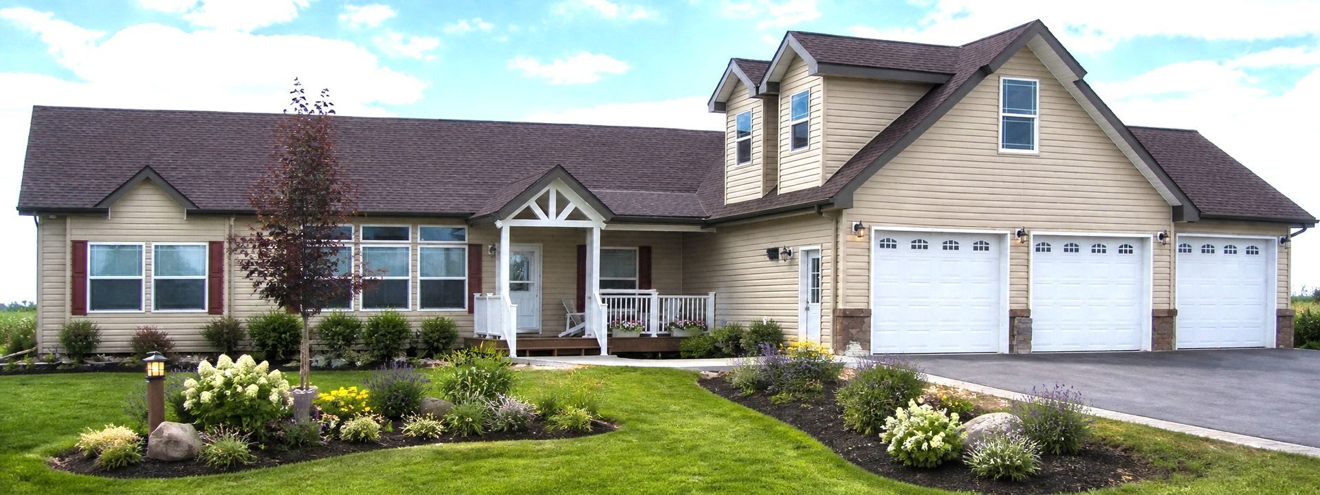 Suburban ranch-style house with beige siding, white garage, and landscaped front yard under a bright sky