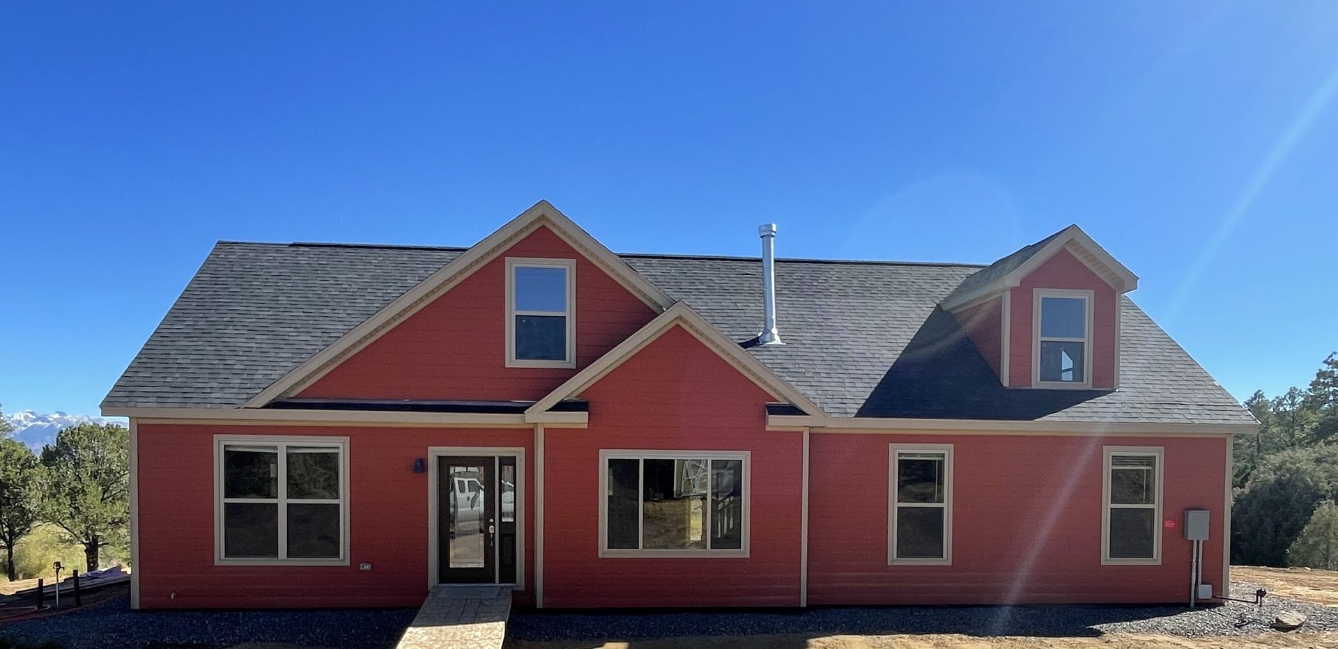 Red house with gray roof and front entrance under a clear blue sky