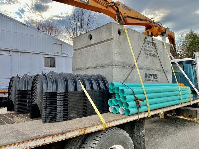 a truck is loaded with pipes and a septic tank
