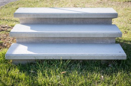 a set of concrete steps sitting on top of a lush green field .