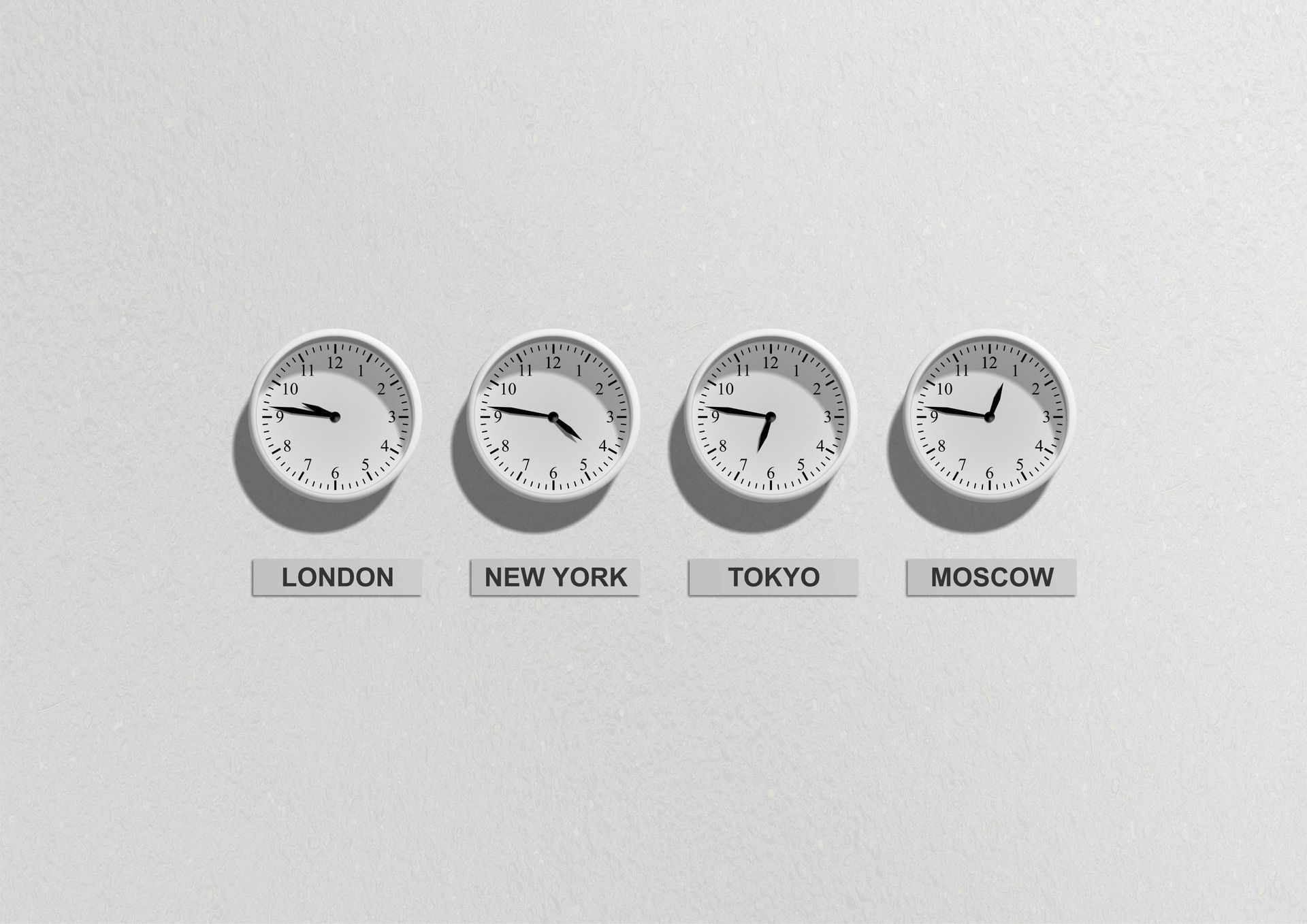 Four clocks on a white wall display different times for London, New York, Tokyo, and Moscow.