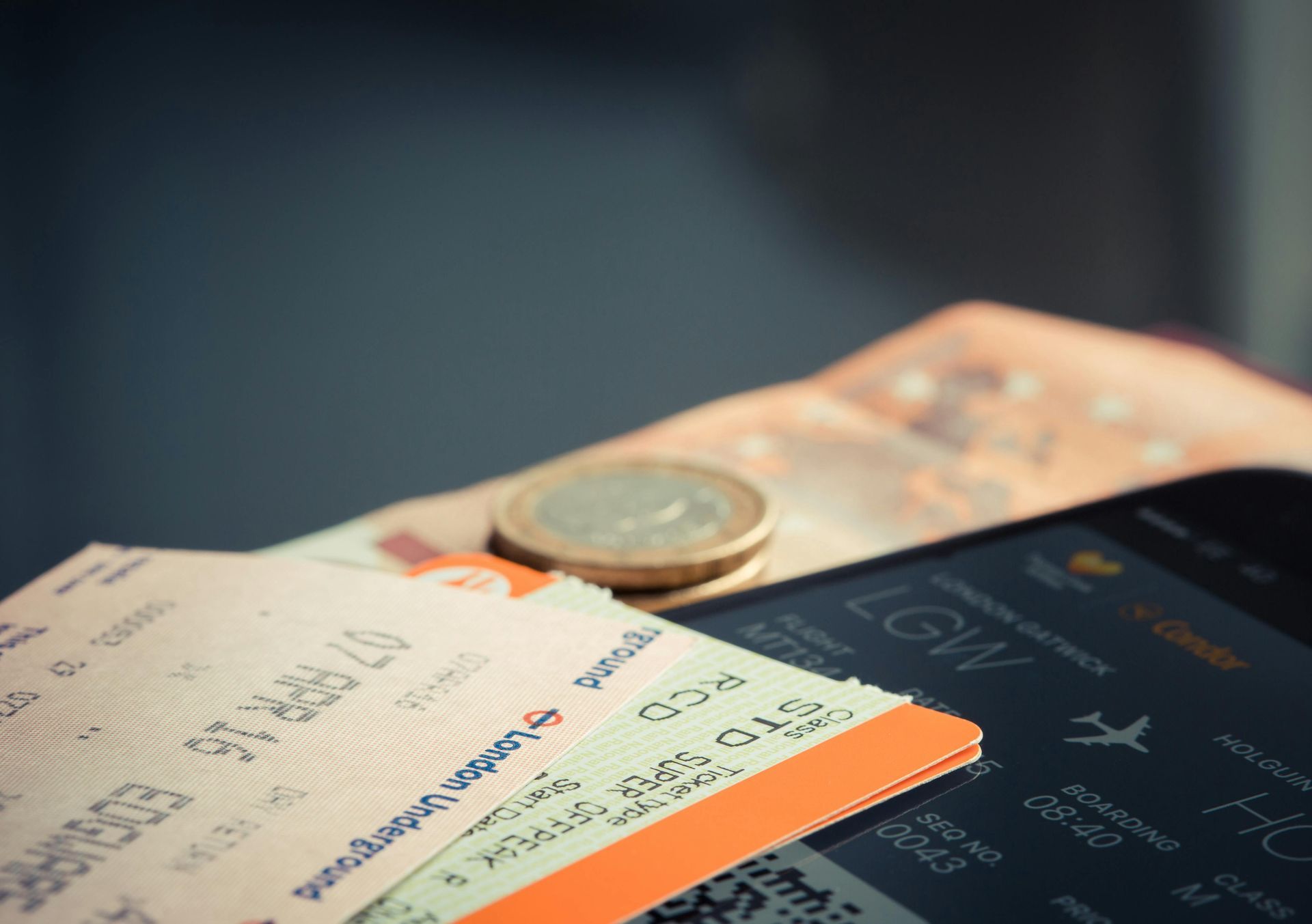 Airline tickets, a smartphone with a boarding pass, and currency including coins, suggesting travel and budgeting.