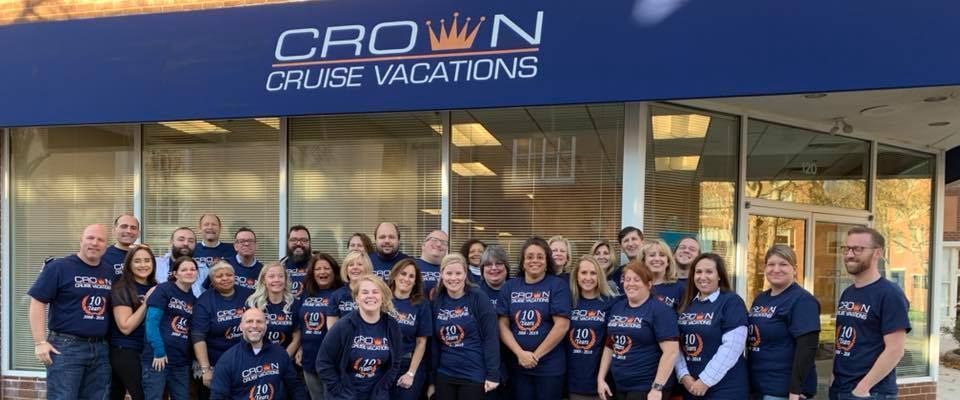 A group of people are posing for a picture in front of a crown cruise vacations building.