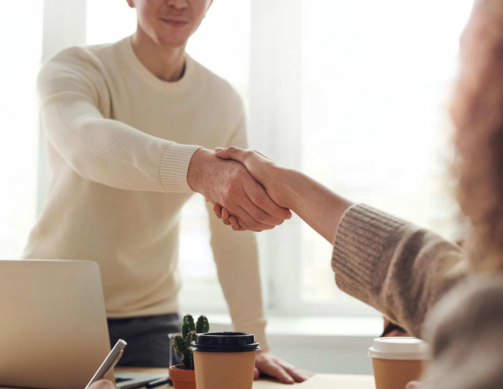 Man shaking hands with a person at a desk, likely an office setting.
