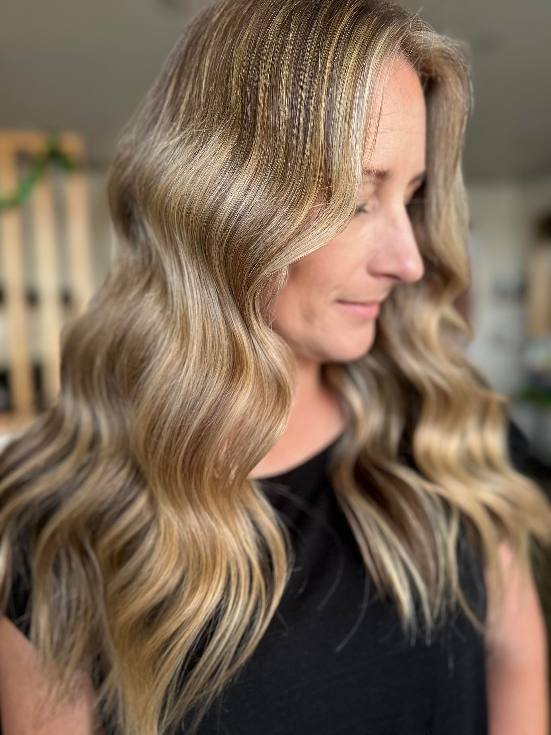 A Woman With Long Blonde Hair Is Wearing A Black Shirt — Arabella Hair Design in Sebastopol, VIC