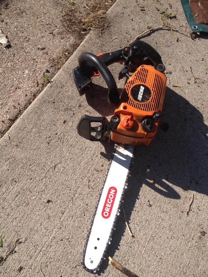 Orange chainsaw with black handle and Oregon blade on concrete.
