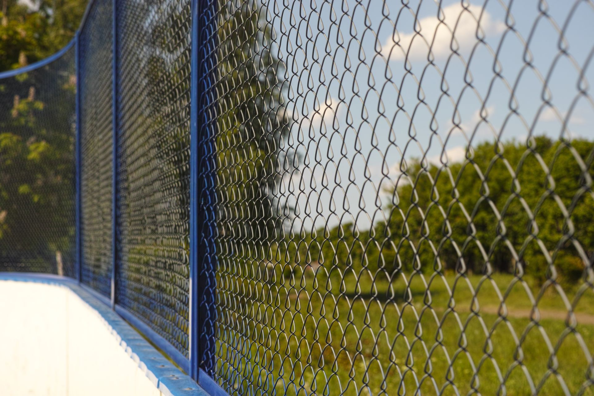 A close up of a chain link fence with trees in the background.