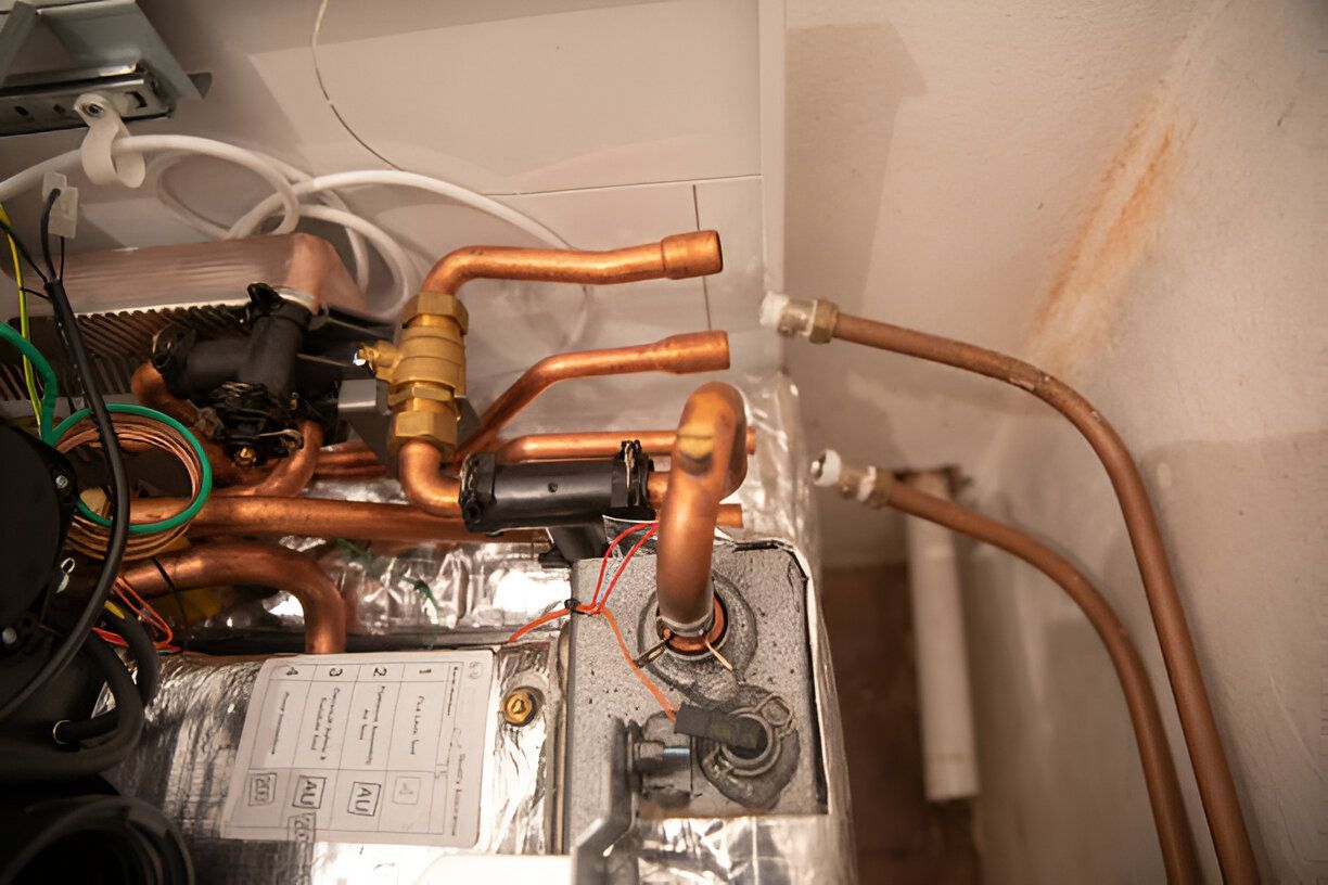 A close up of a boiler with copper pipes and wires.