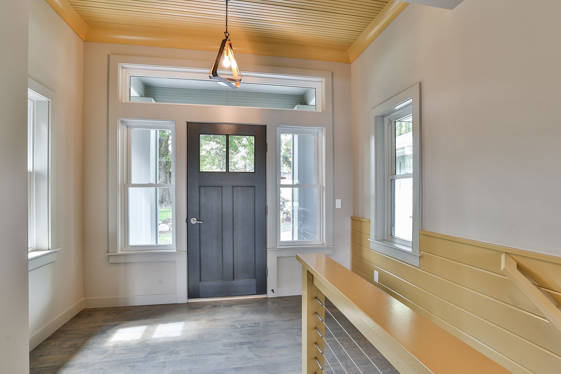 Entryway with gray door, three windows, wooden ceiling, and a light fixture.