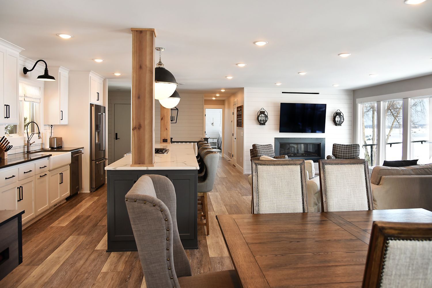 Open-concept kitchen and living area with island, cabinets, fireplace, and dining table; wood floors.