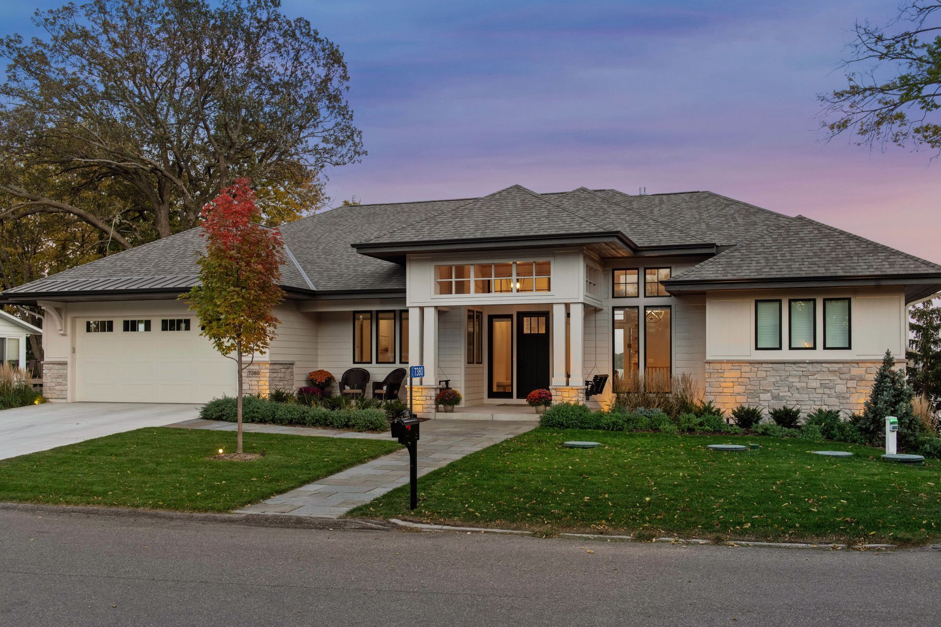 Modern single-story home with a white exterior, gray roof, and a well-manicured lawn.