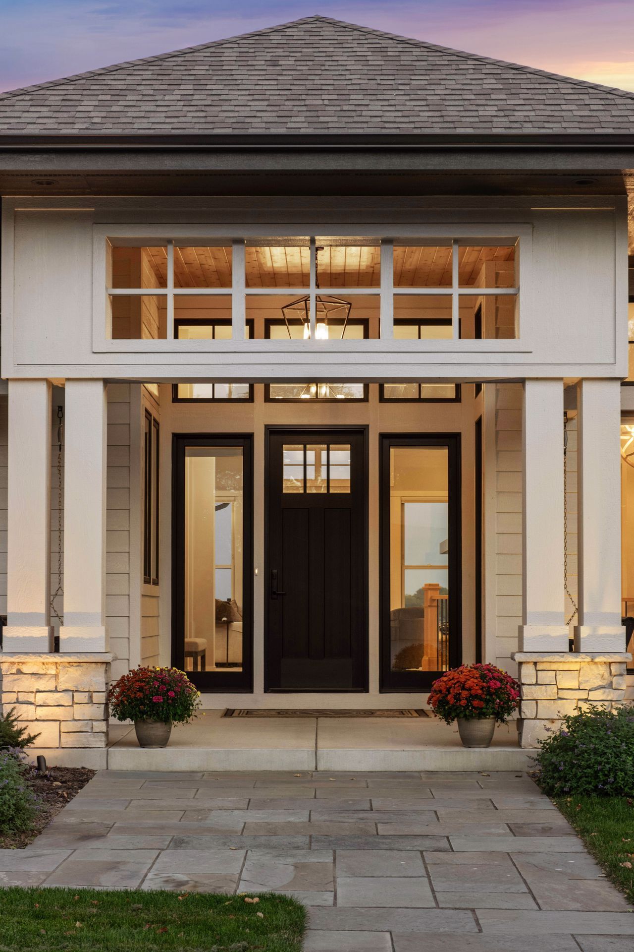 Front entryway with dark door, glass side panels, and overhead windows; cream columns.