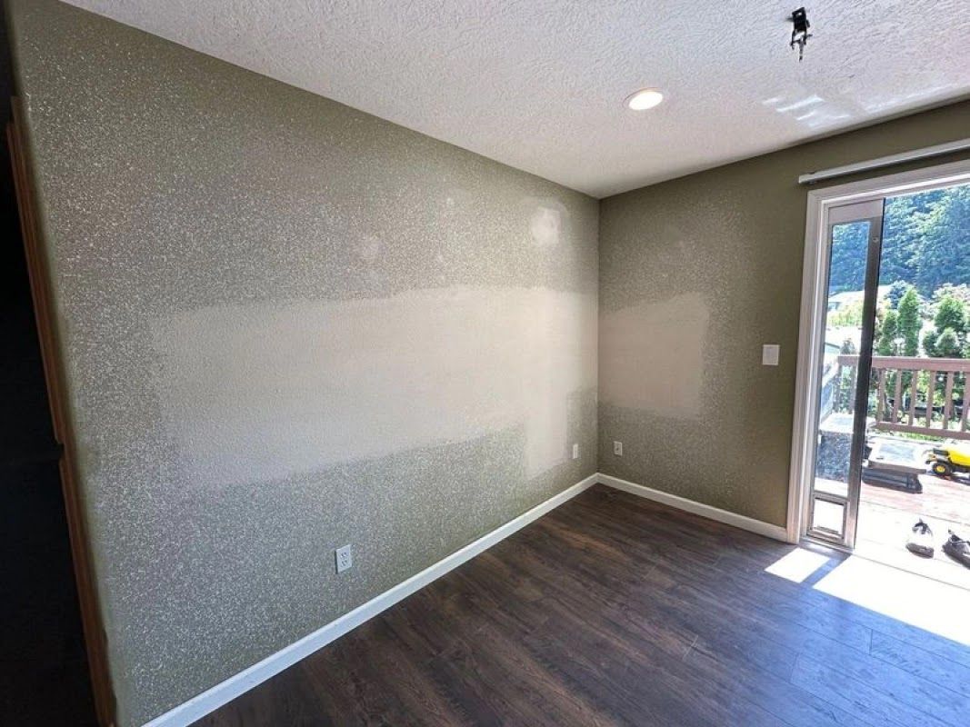 Room with glitter-textured walls, dark wood floor, and sliding door to a balcony. Light patches on the wall.