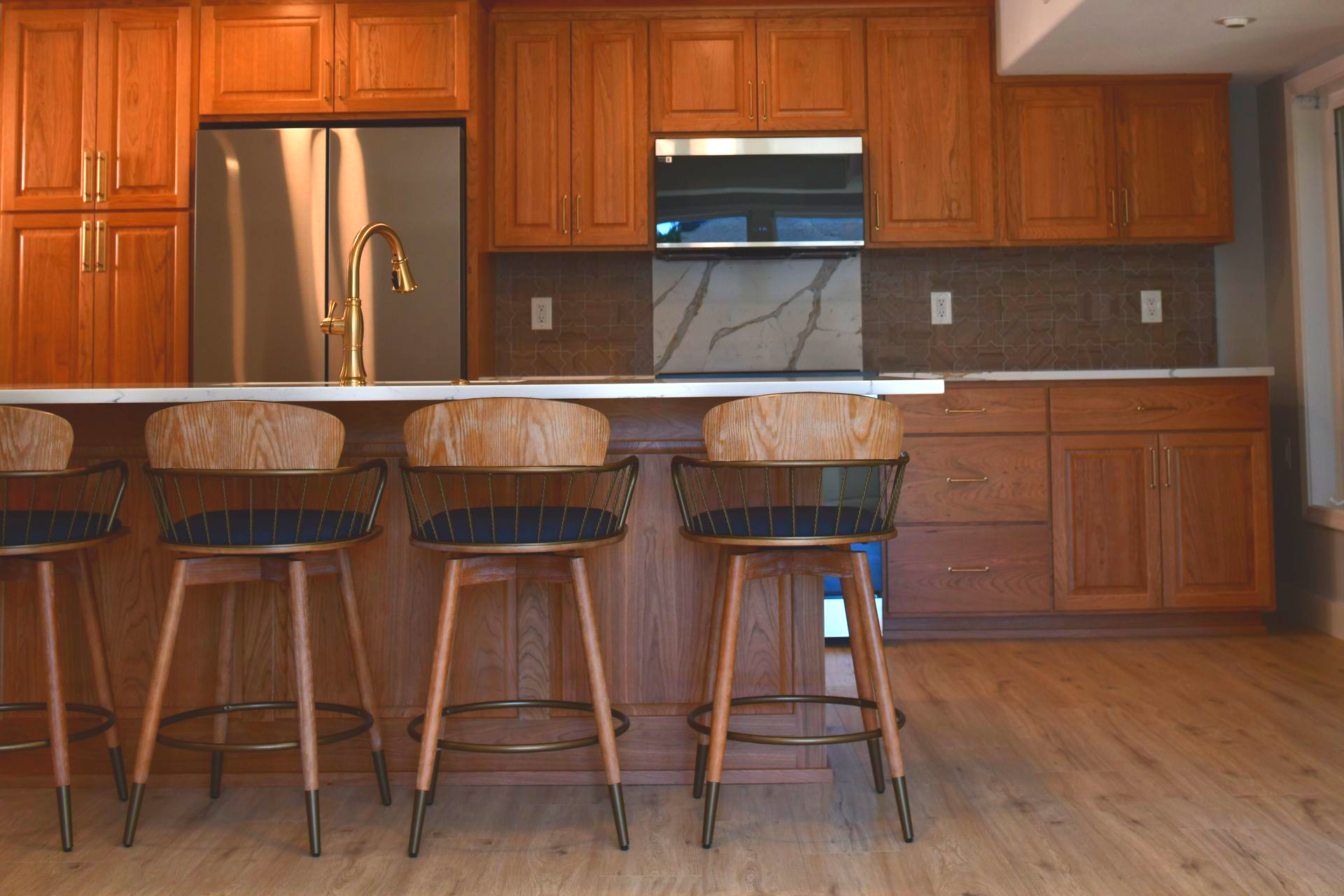 Kitchen with wooden cabinets, island with stools, and stainless steel appliances.
