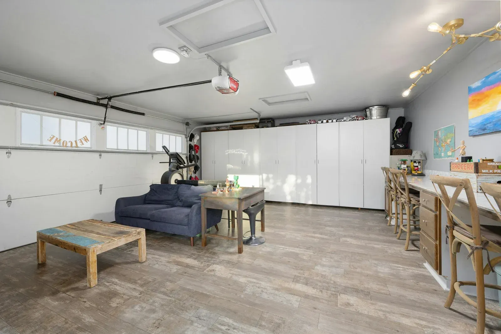 Garage converted into living space with furniture, white cabinets, and a bar.
