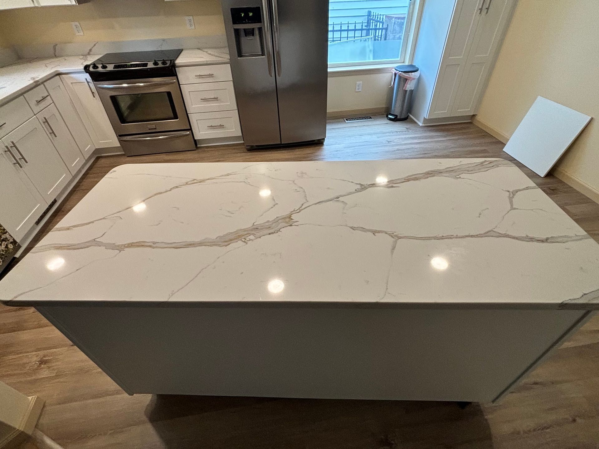 Kitchen with white countertops and cabinets, stainless steel appliances, and a large island with a light-colored countertop.