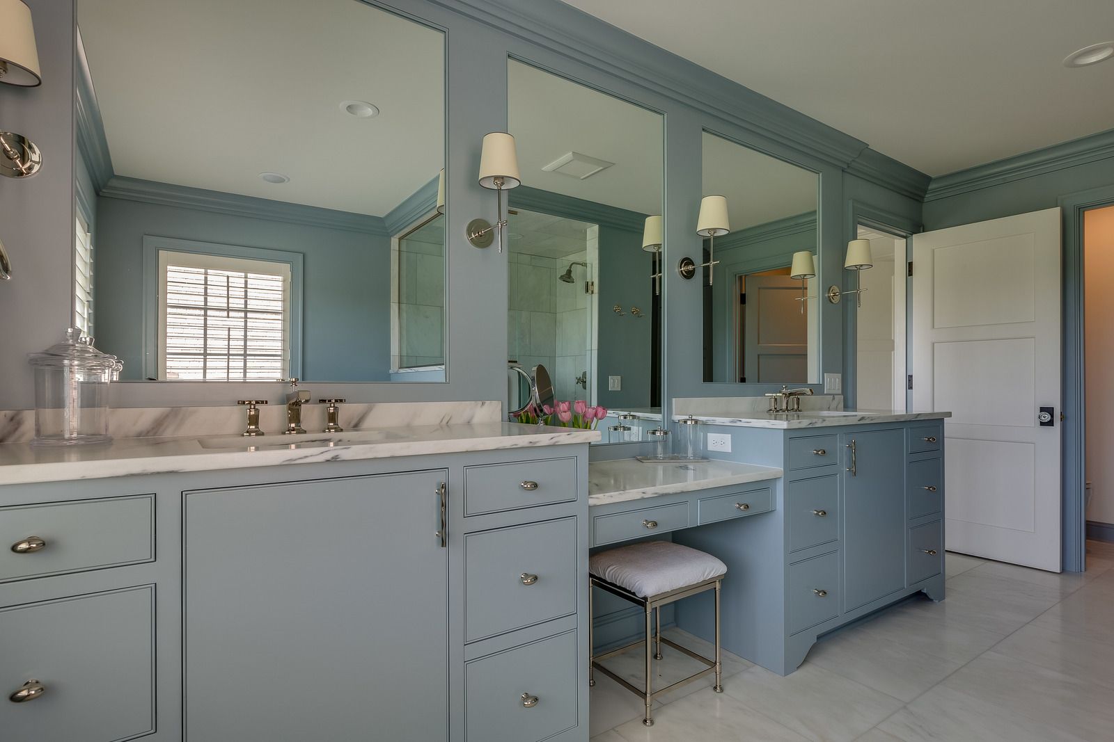 Blue and white bathroom with three mirrors, double sinks, and a vanity.