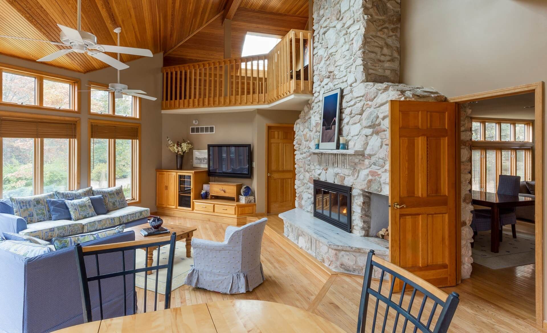 An Airbnb living room with a stone fireplace and a ceiling fan