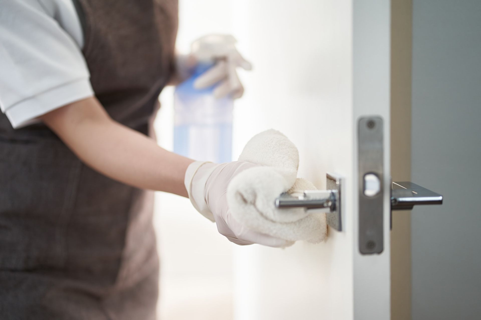 A person is cleaning a door handle with a towel.