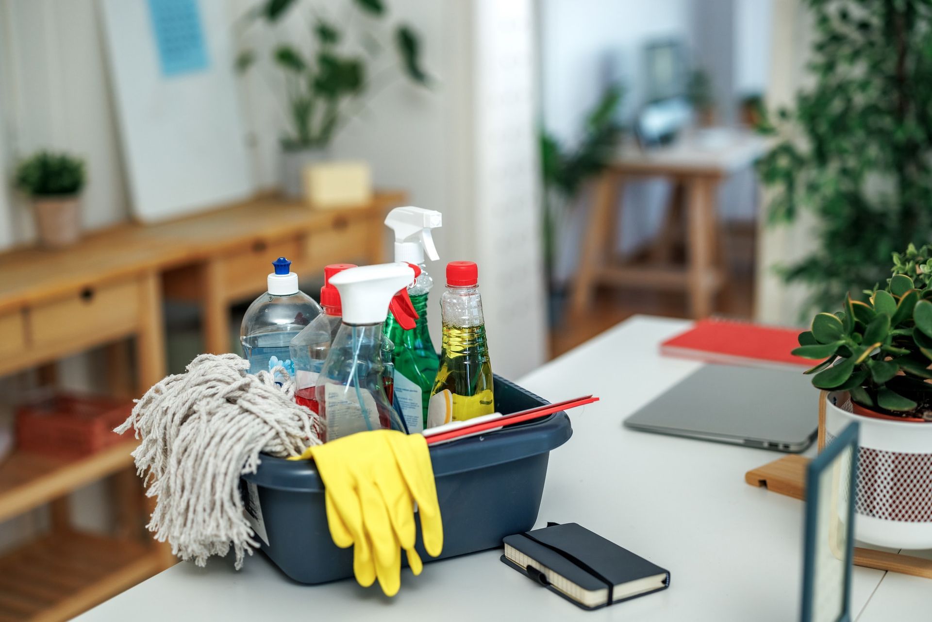 A basket filled with cleaning supplies is sitting on a desk.