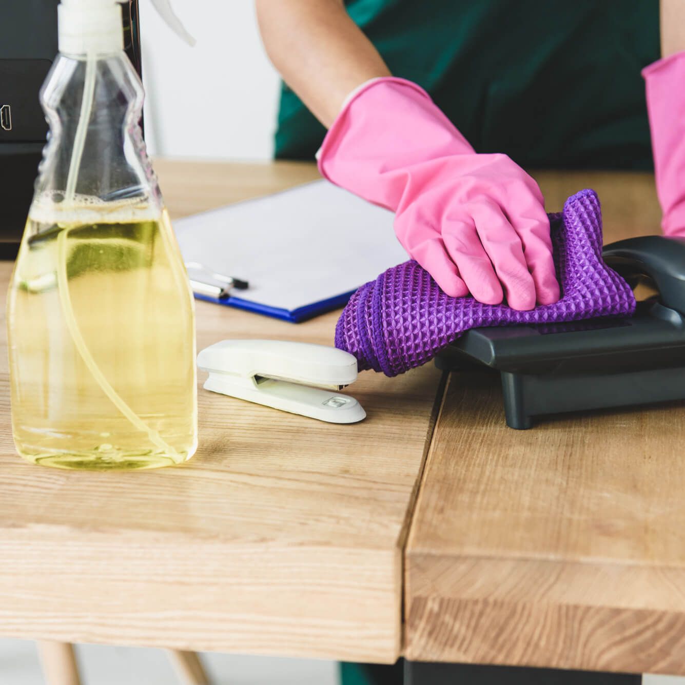 A person wearing pink gloves is cleaning a phone with a purple cloth