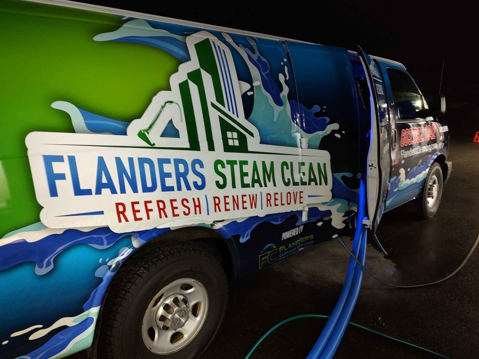 A Flanders Steam Clean work van with green and blue graphics parked at night with hoses running from the interior.