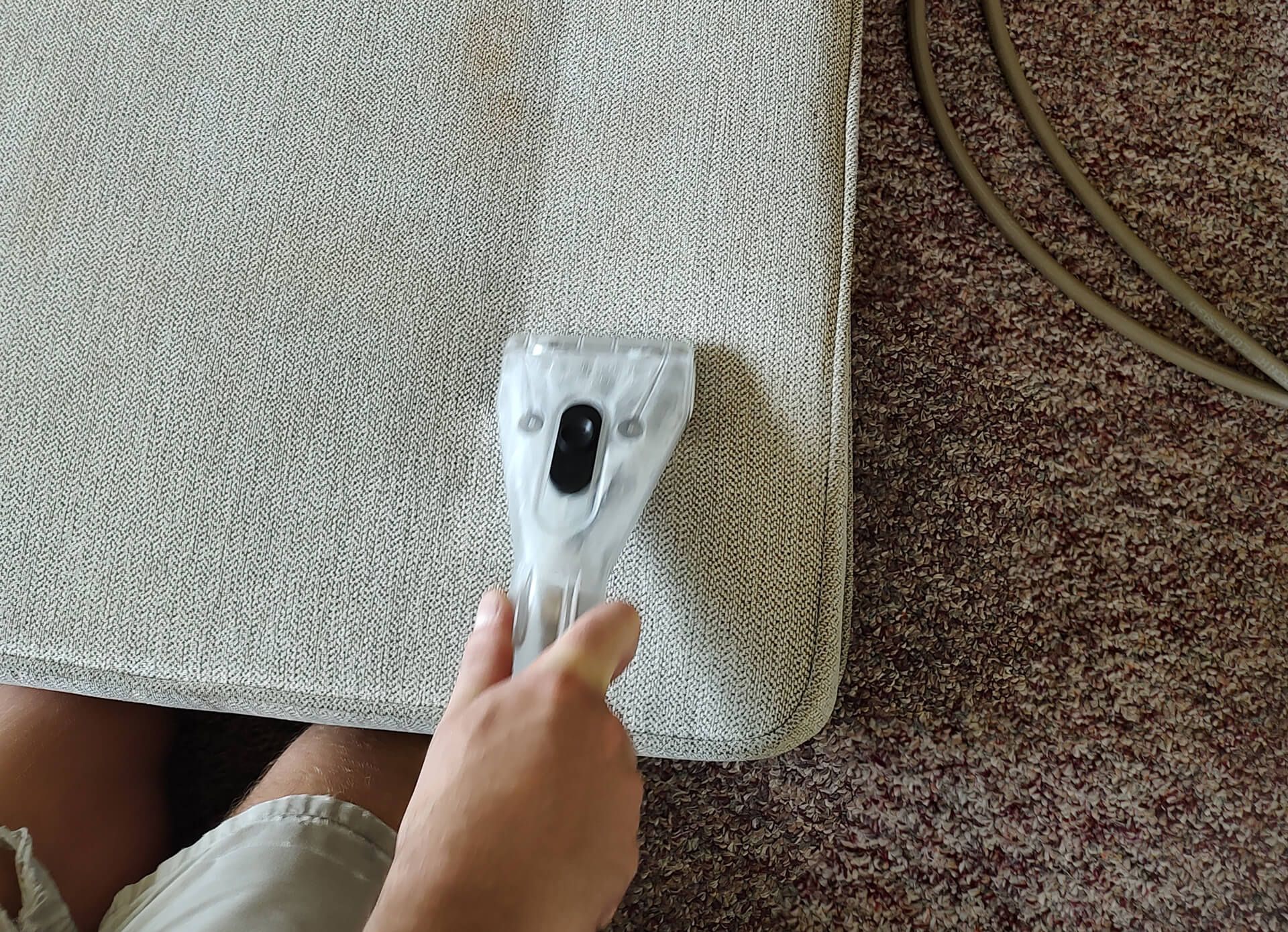 A person is cleaning a carpet with an upholstery cleaner.