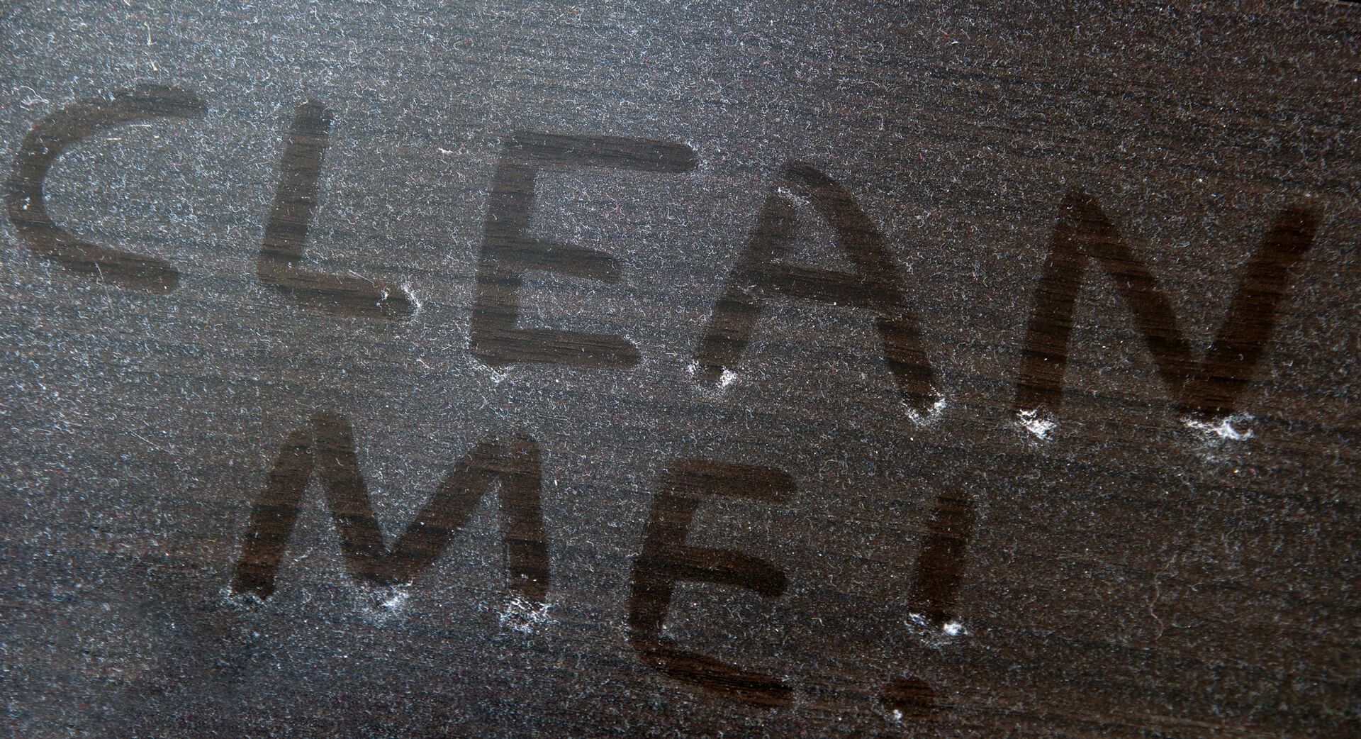 The word clean is written on a black surface covered with dust