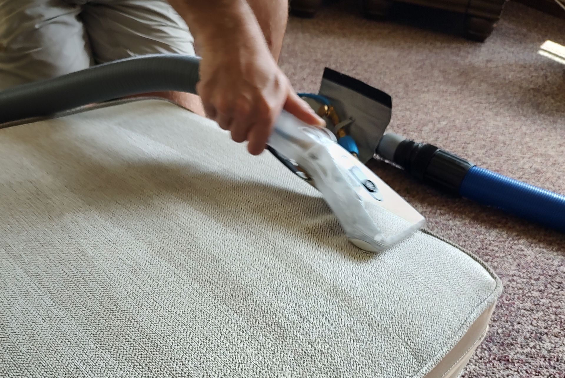 A person is cleaning a carpet with a vacuum cleaner