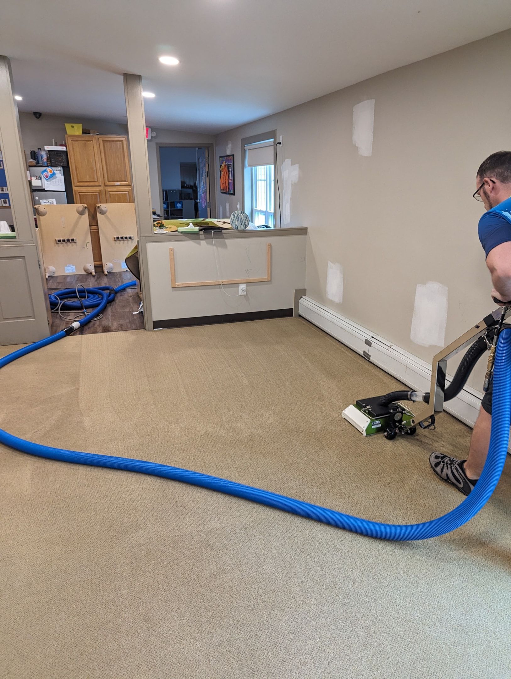 A man is using a vacuum cleaner to clean a carpet in a room.