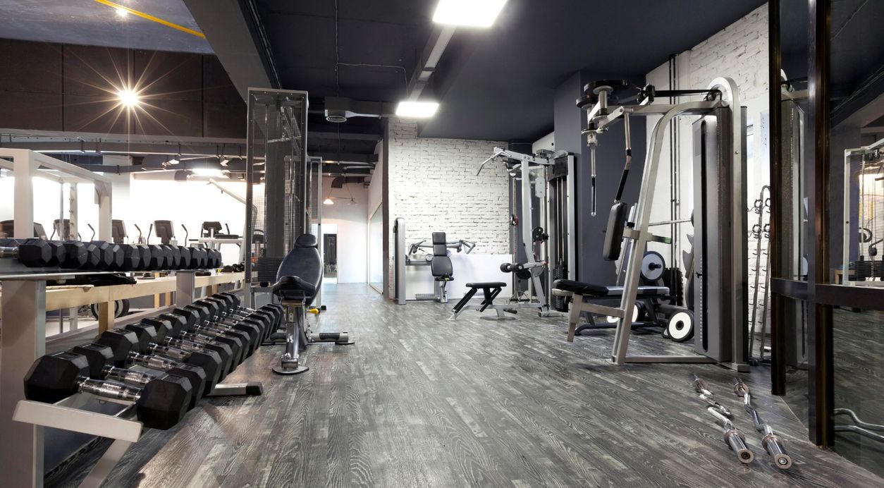 A gym with a lot of dumbbells and exercise equipment.