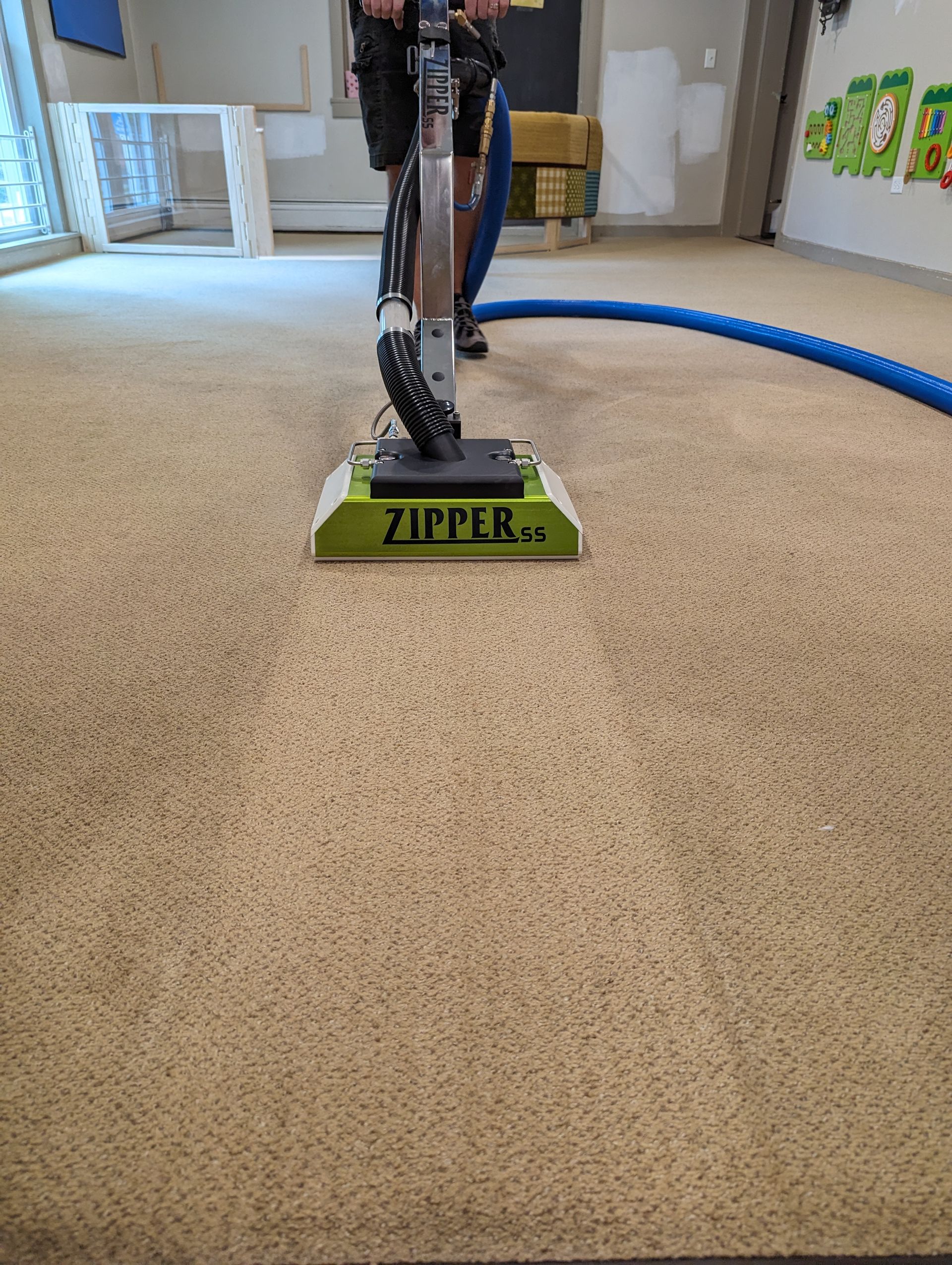 A person is using a vacuum cleaner to clean a carpet in a room.