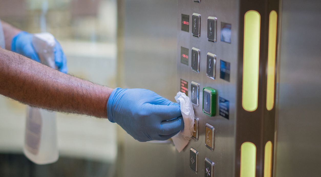 a person wearing blue gloves is cleaning the buttons on an elevator cleaned by flanders cleaning services