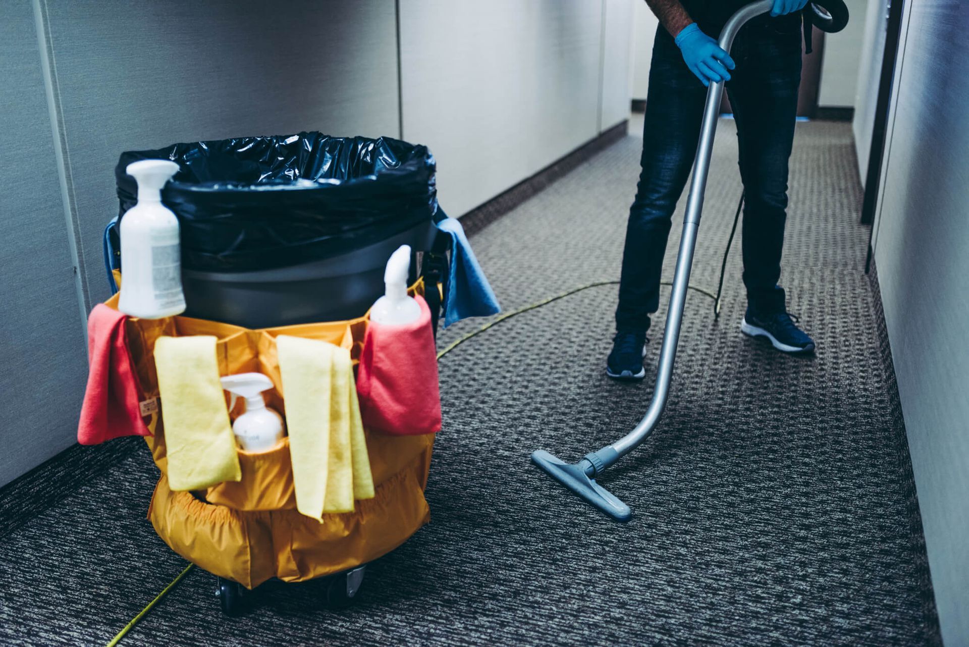 A man is cleaning a hallway with a vacuum cleaner.