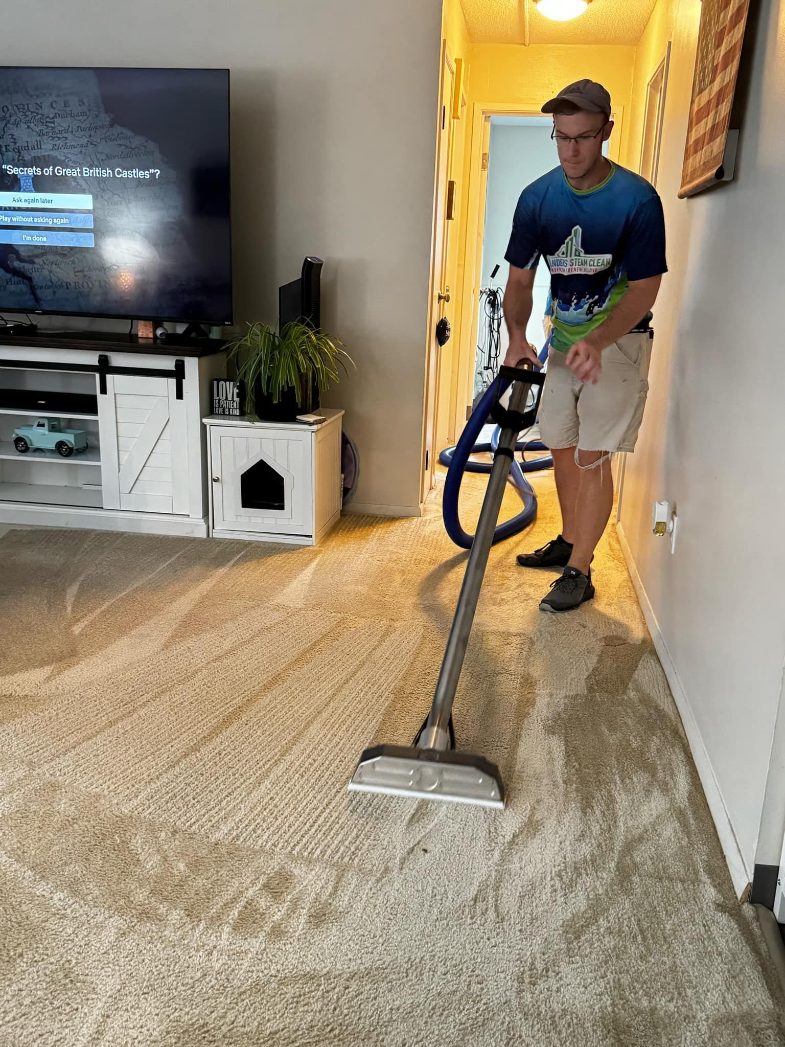 A man is using a vacuum cleaner to clean a carpet in a living room.