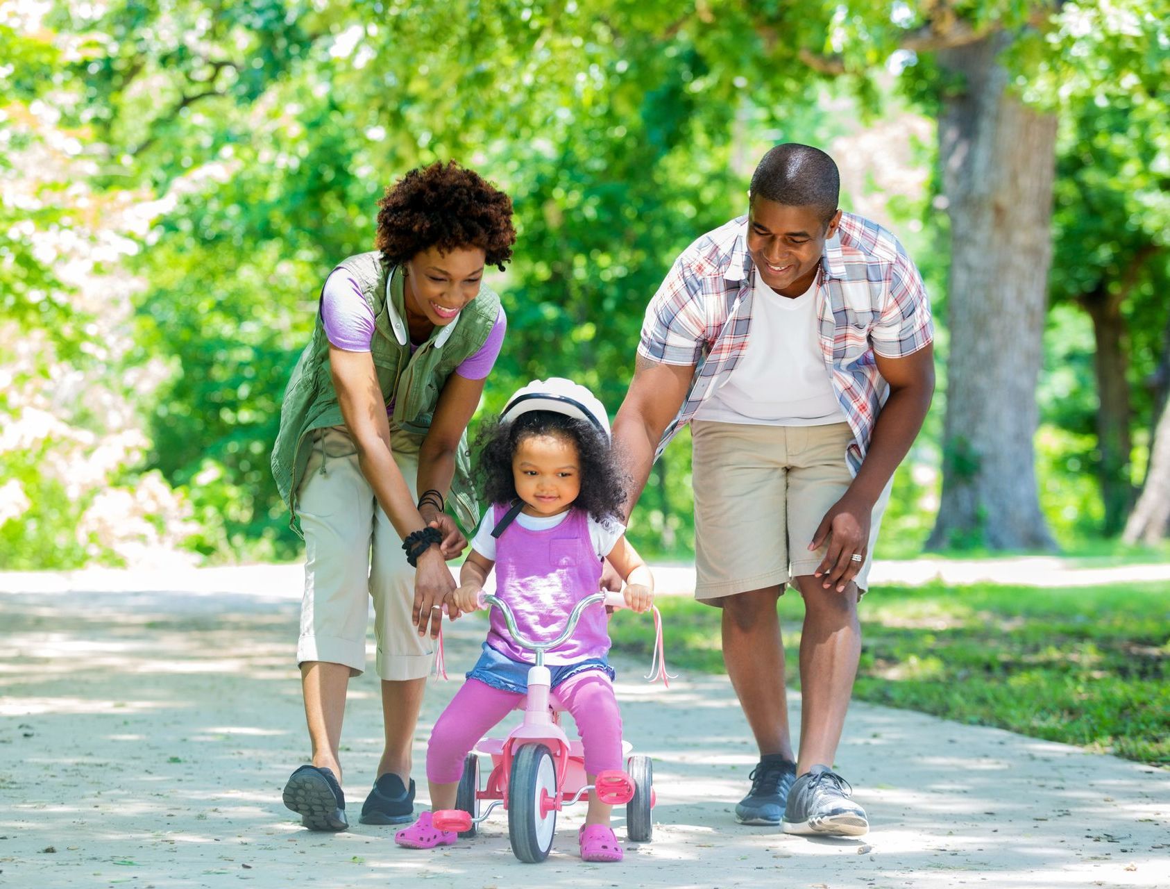 Mother and father with child on tricycle.