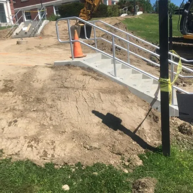 A construction site with stairs and a cone on the ground