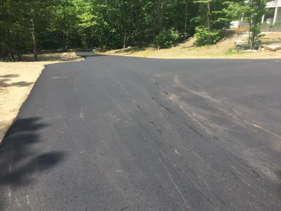 A black asphalt road with trees in the background.