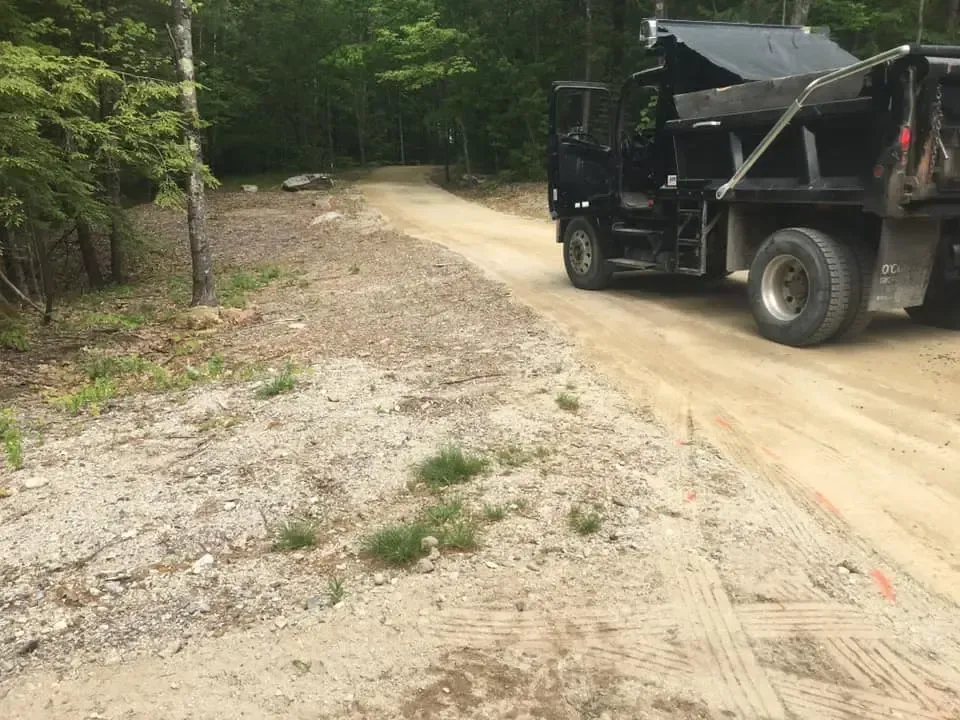 A dump truck is driving down a dirt road.