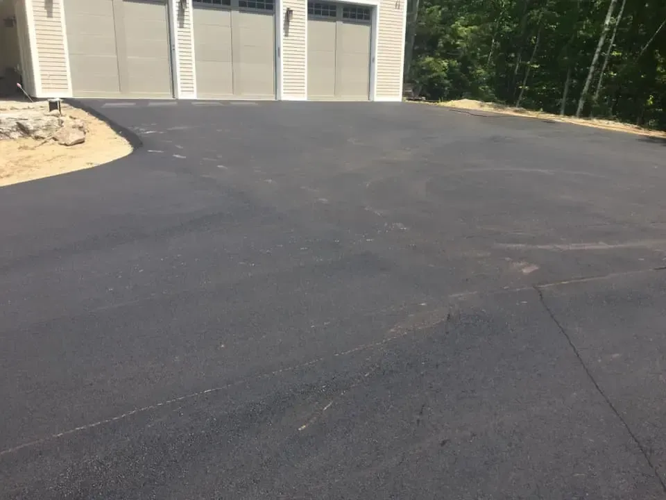 A driveway with a garage in the background and a house in the background.