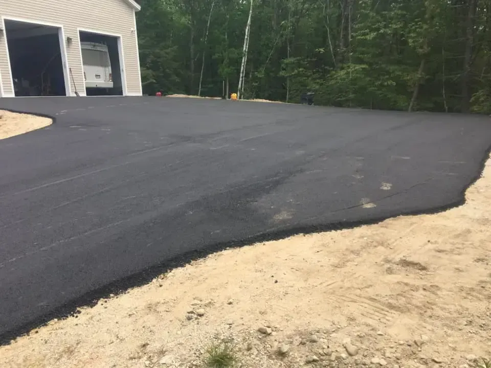 A newly paved driveway with a garage in the background.