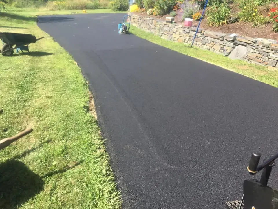 A black asphalt road with a wheelbarrow on the side of it.