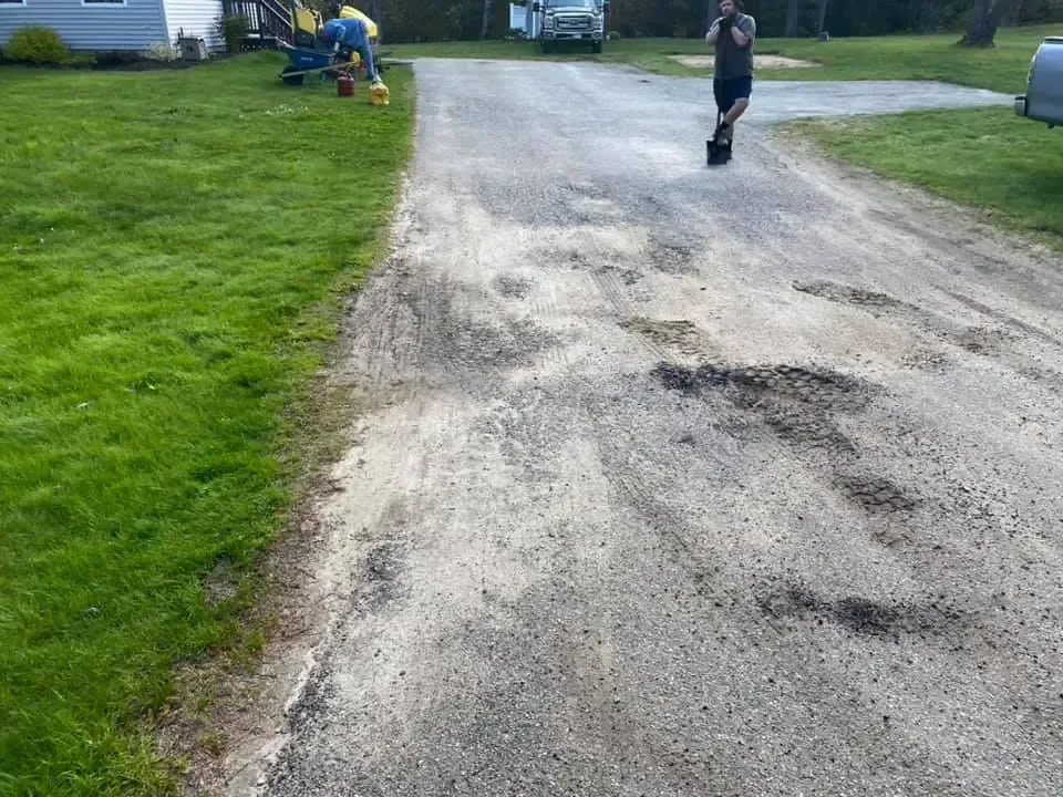A man is standing on the side of a dirt road.