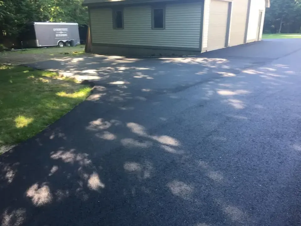 A driveway leading to a garage with a trailer in the background.