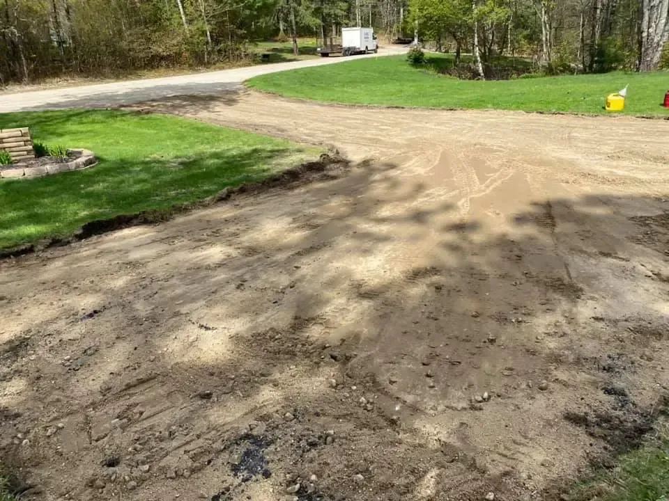 A dirt road going through a lush green field.