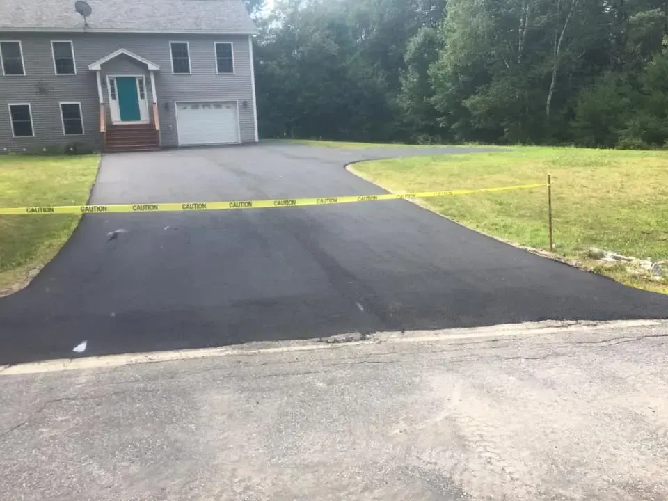 A driveway leading to a large house with a green door.