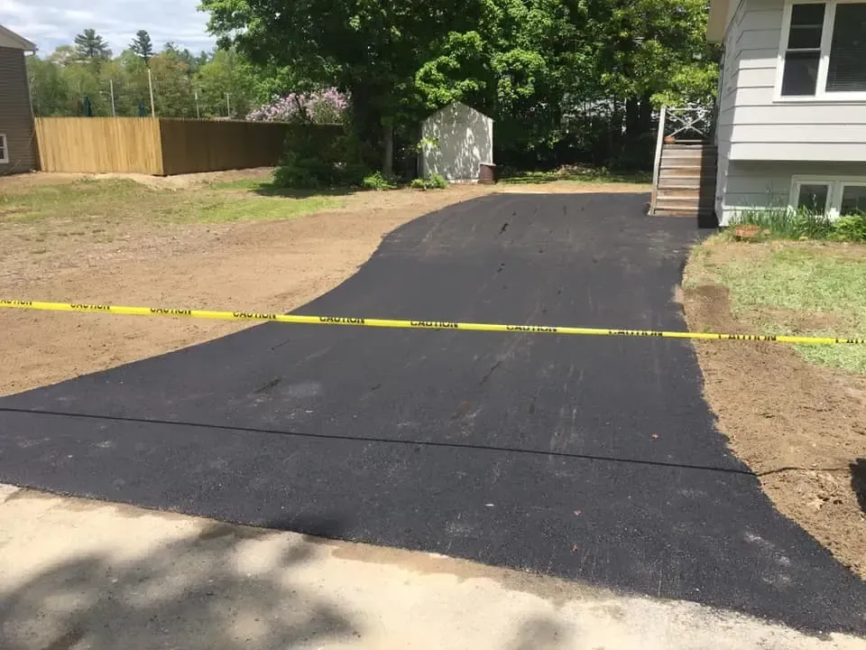 A newly paved driveway is surrounded by yellow tape.
