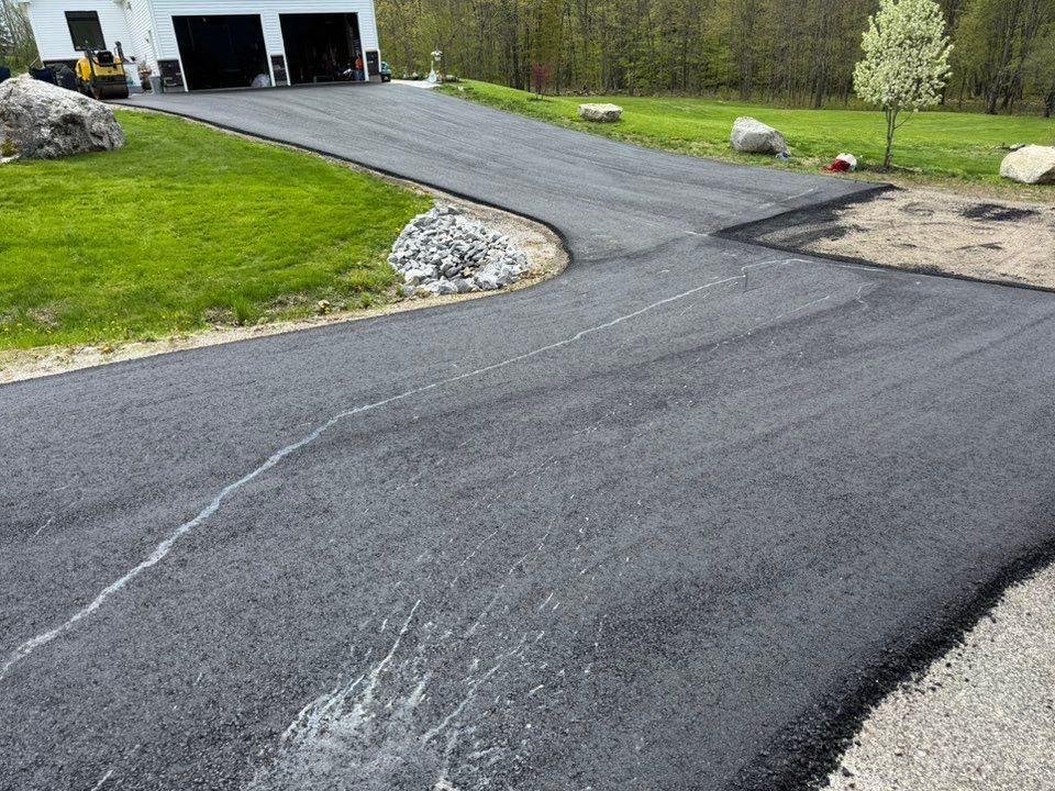 A asphalt driveway is being built in front of a house.