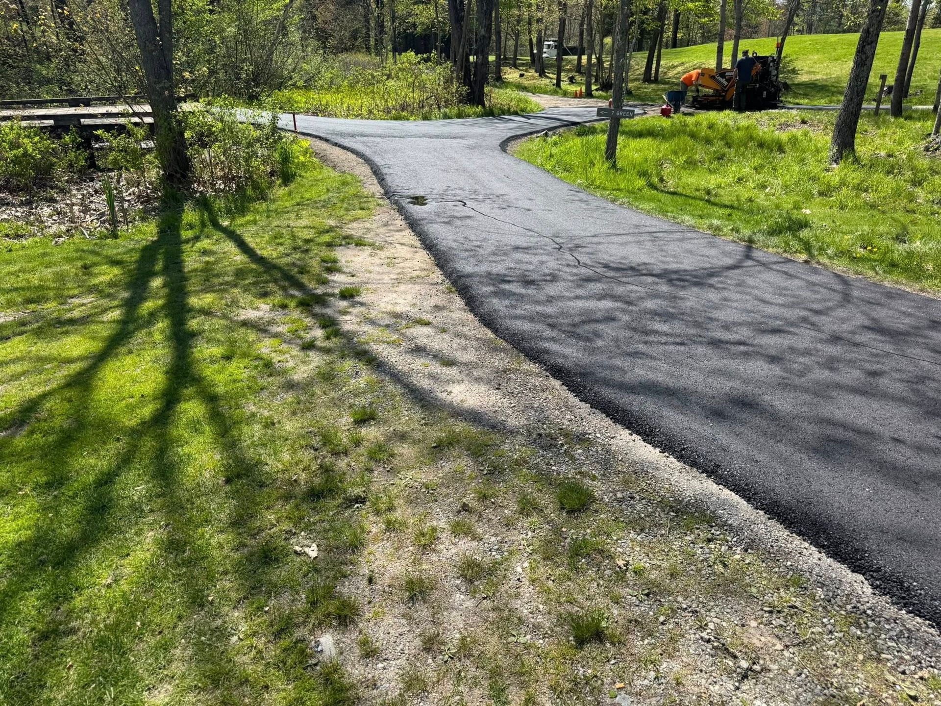 A newly paved road going through a grassy field.